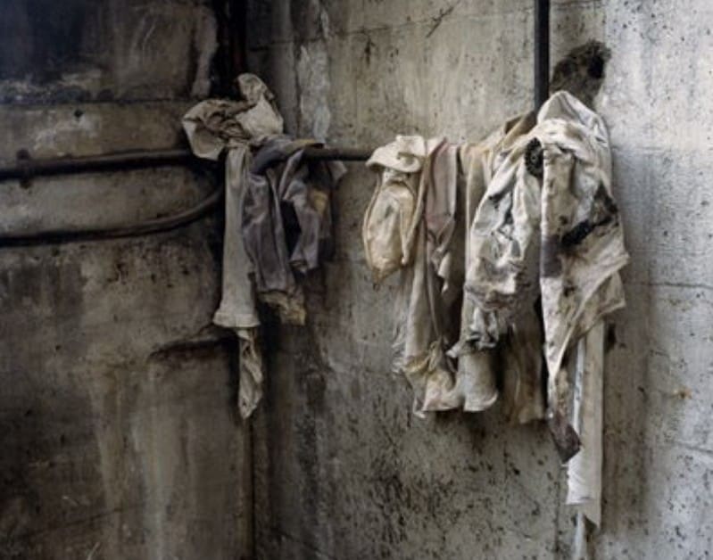 Old filthy rags hanging on hooks on a dirty wall.